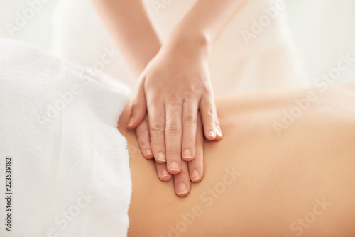 Quadro su tela Crop hands of female therapist rubbing loin of female client during massage sess