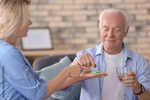 Doctor giving medicine to senior man at home