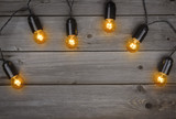 Christmas glowing electric light bulbs garland on dark wooden background
