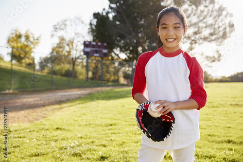 Chinese schoolgirl holding baseball and mitt smiling photo