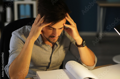 Tired man working late in e...