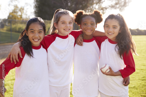 Canvas Print Schoolgirl baseball team embracing and holding a baseball