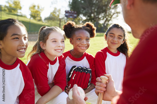 Photography Girl baseball team in a team huddle listening to the coach