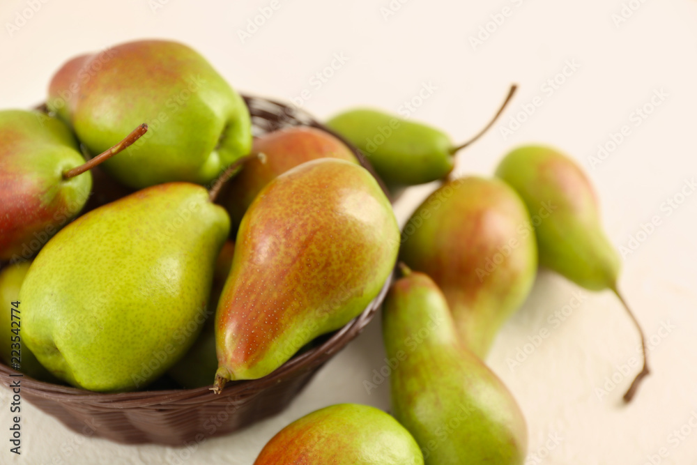 Wicker bowl with ripe sweet pears on white table