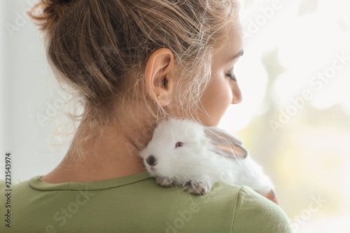 Beautiful young woman with cute rabbit at home photo