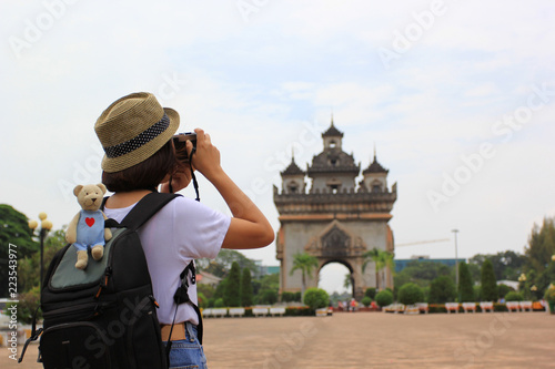 Happy hipster girl holding camera in his hands with talking pictures on Patuxai or Patuxay monument in Vientiane, Laos, Travel lifestyle vacations concept photo