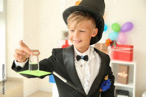 Foto Cute little magician showing trick indoors