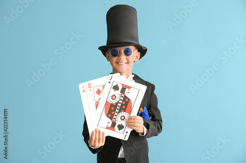 Foto Cute little magician with cards on color background