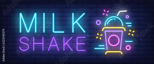 Milk shake neon sign. Colorful takeaway cup with cap and straw on brick wall background. Vector illustration in neon style for ice cream shop children party and cafe