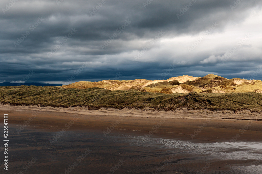 View at the beach, with dramatic clouds and the mountains off in the distance