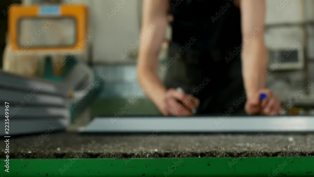 Production of PVC windows from the profile, the male worker marks the dimensions on the pvc profile, for further assembly of the PVC window, manufacturing marker Production of PVC windows from the profile, the male worker marks the dimensions on the pvc profile, for further assembly of the PVC window, manufacturing marker