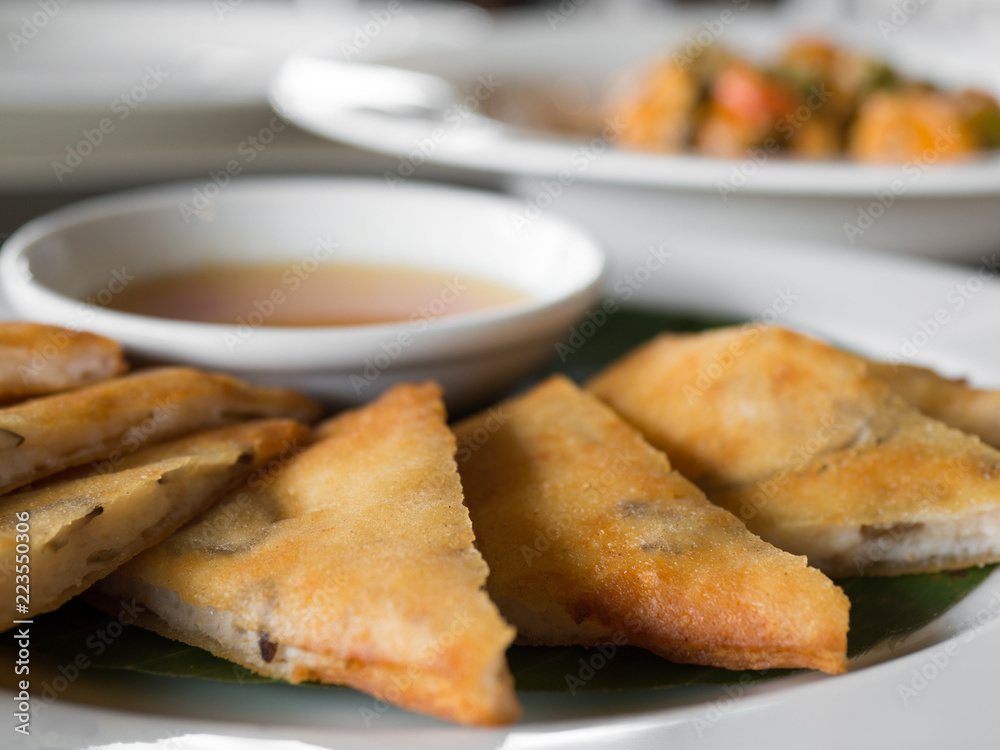 close up of crispy spring roll stuffed with prawns and pork on a white plate in a restaurant