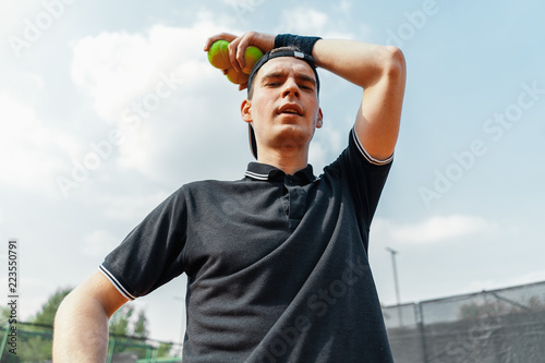 Close up of young man relaxing after tournament and holding tennis balls. © Akaberka