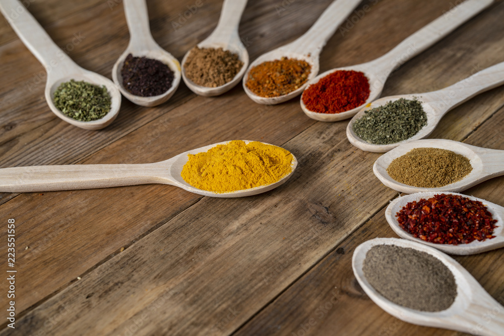 Assorted spices on wooden spoons. Delicious food ingredients.