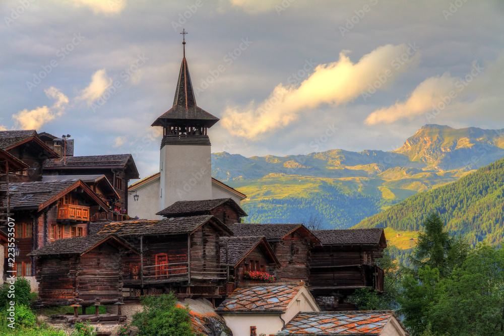 Beautiful cityscape of the alpine village Grimentz, Switzerland, with traditional wooden houses and church tower in summer