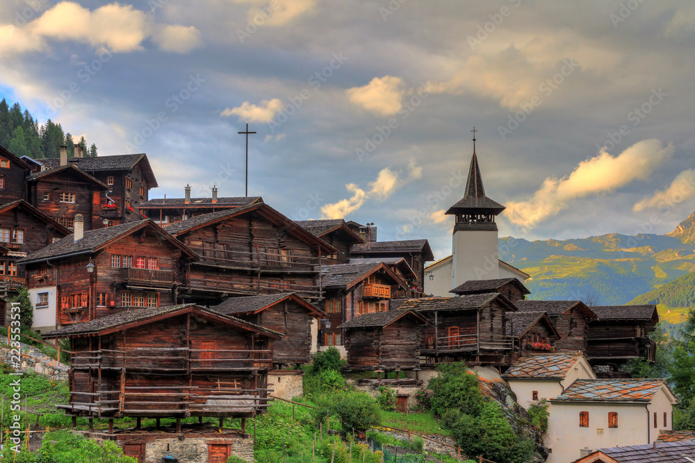 Beautiful cityscape of the alpine village Grimentz, Switzerland, with traditional wooden houses and church tower in summer