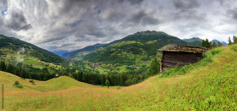 Fototapeta premium Beautiful panoramic view of the Val d’Anniviers valley in Switzerland with the villages saint-luc, saint-jean and vissoie in summer with a green meadow and a shed