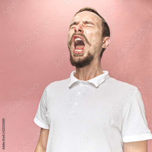 Konstfotografi Young funny handsome man with beard and mustache sneezing with spray and small drops, studio portrait on pink background