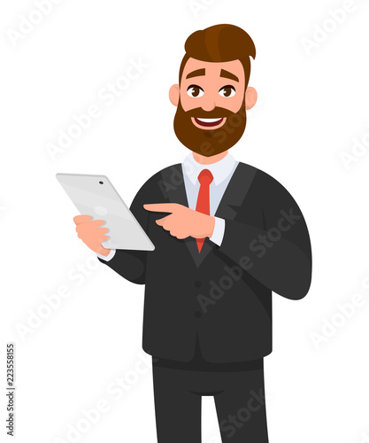 Happy confident business man holding or using a tablet computer. Business man standing isolated in white background gesturing hand using tablet PC.