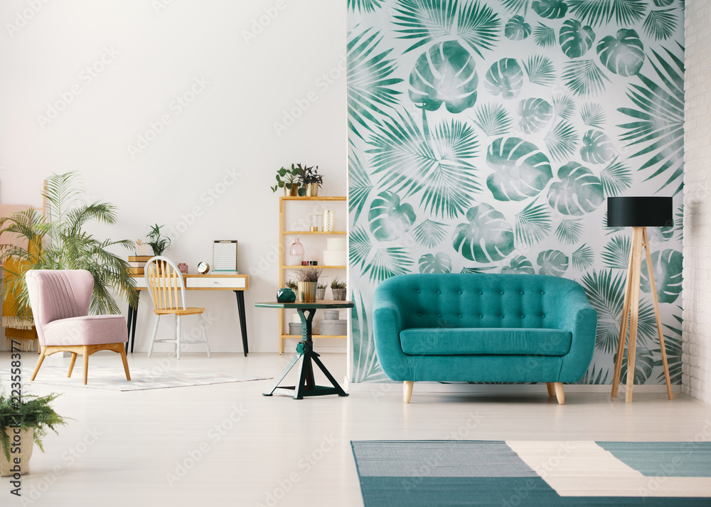 White living room interior with leafy wallpaper in the real photo with  turquoise sofa, fresh plants, wooden desk and empty wall with place for  your poster Stock Photo | Adobe Stock