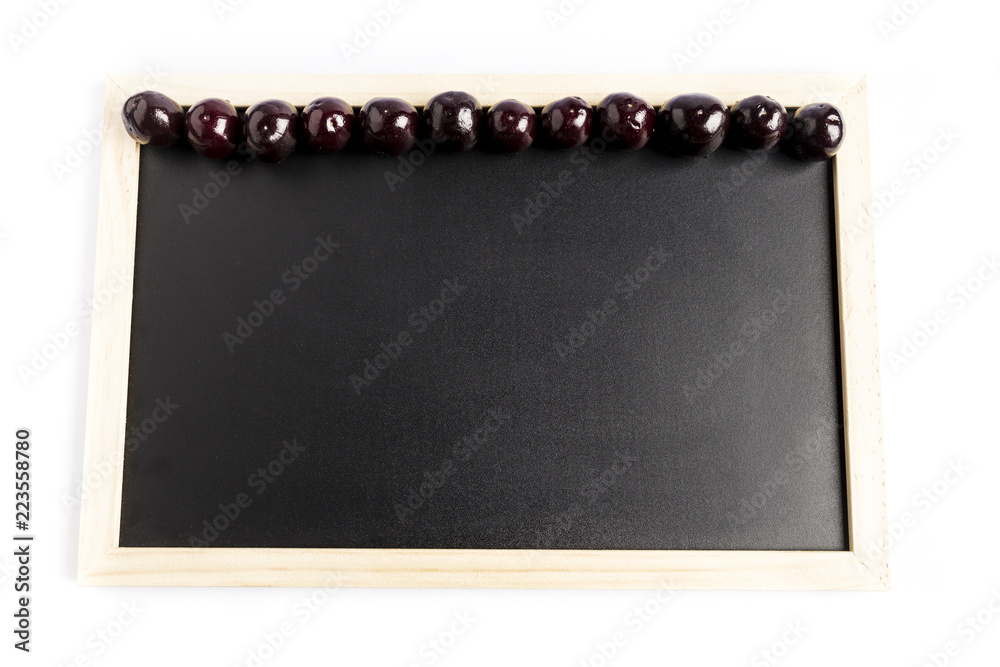 Obraz premium group of fresh red cherries in a row on a black chalkboard with a white background 