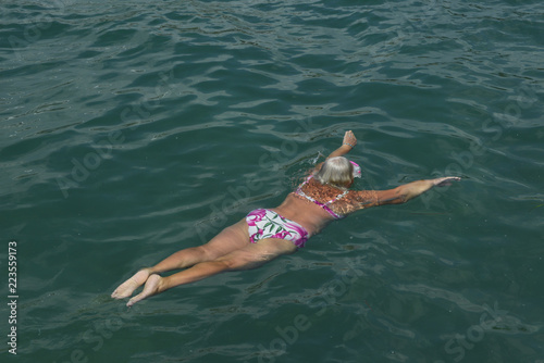 Aged woman is swimming with swim mask in the sea.