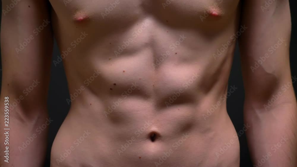Muscular fit torso and biceps of caucasian athlete who standing powerfully next to camera in studio Muscular fit torso and biceps of caucasian athlete who standing powerfully next to camera in studio