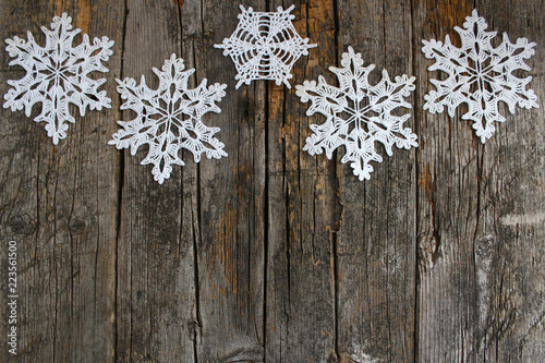 White crochet snowflakes on vintage rural wooden background. The concept of the celebration, new year and Christmas