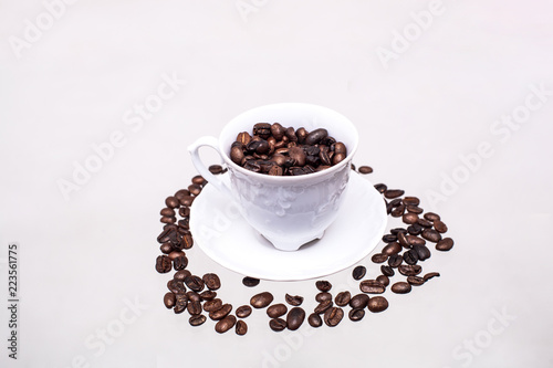 The white cup is filled with coffee beans