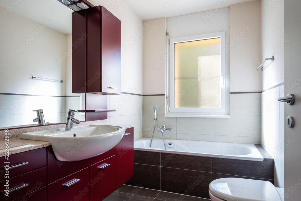 Bathroom with red wardrobe, bathtub and window Bathroom with red wardrobe, bathtub and window