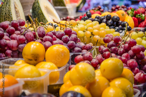 punnets of fresh plums and grapes on sale on a market stall.