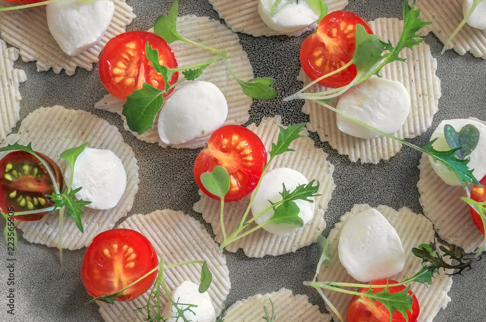 Mozzarella and tomatoes with thyme, arugula and Basil are on corn chips. Preparation of canapes.