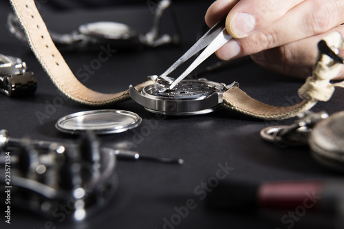 Detail of the work of a watchmaker who replaces a battery / Close up of replacing a watch battery with watchmaker tools photo