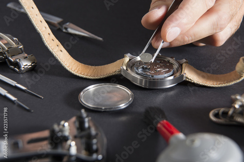 Detail of the work of a watchmaker who replaces a battery / Close up of replacing a watch battery with watchmaker tools