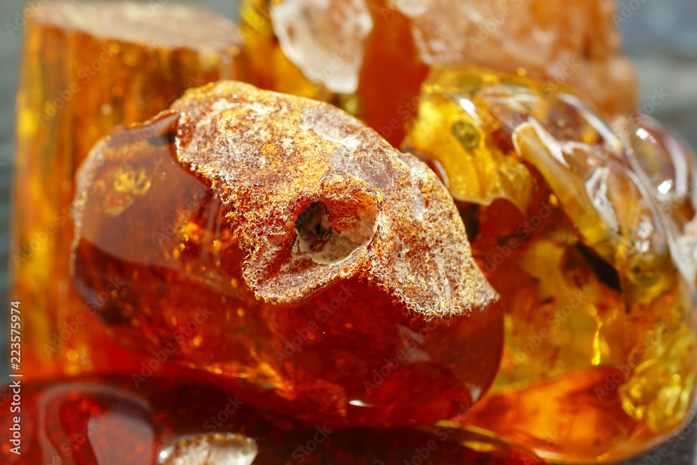 Amber texture with a natural crust. Fossil resin for jewelry. A sunny  stone. Natural mineral. Crystal. Ancient vintage jewelry. Amber with insect  inside as a background. Many pieces of amber Stock Photo
