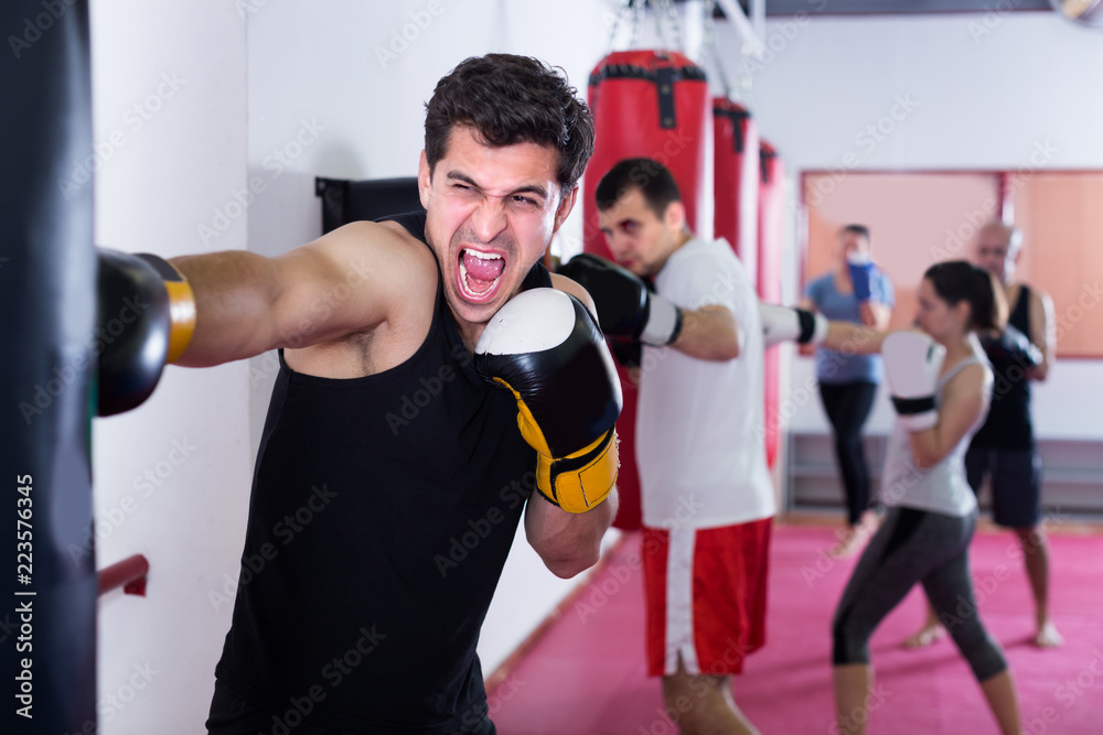 Muscular man is beating a boxing bag