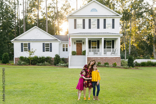 Mom and Two Daughters Hugging Outside their New Farmhouse Home