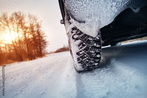 Car tires on winter road covered with snow. Vehicle on snowy way in the morning at snowfall photo