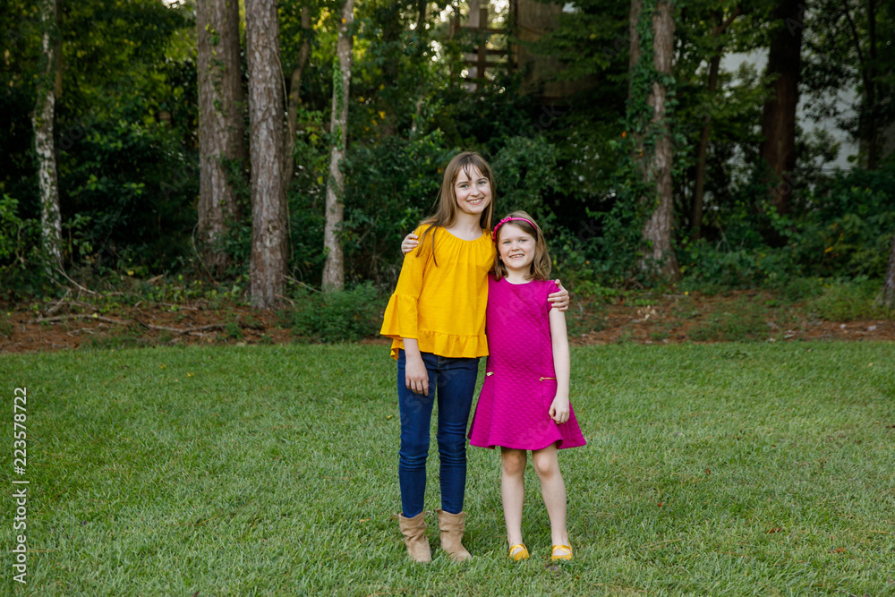 Fototapeta premium Beautiful Sisters in Their Backyard Hugging