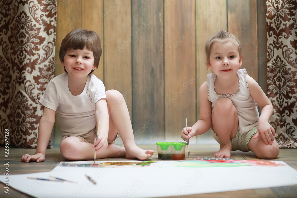 Little children paint on a large sheet of paper Little children paint on a large sheet of paper