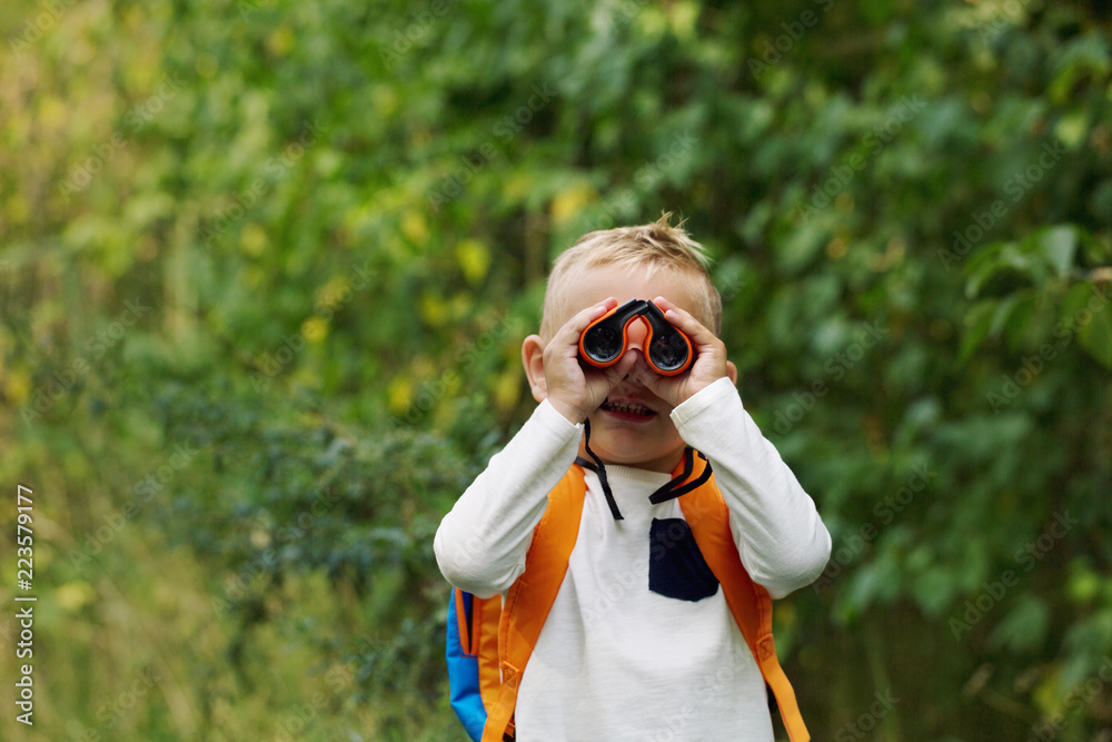 The little boy young researcher exploring with binoculars and backpack environment The little boy young researcher exploring with binoculars and backpack environment