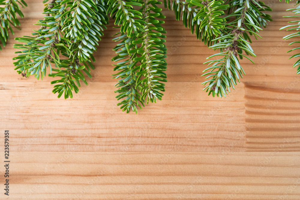Green fresh Christmas tree pine branches on natural wooden background. Copy space on the bottom. Green fresh Christmas tree pine branches on natural wooden background. Copy space on the bottom.