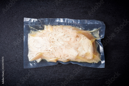 Chicken breast vacuum sealed on black table, from above