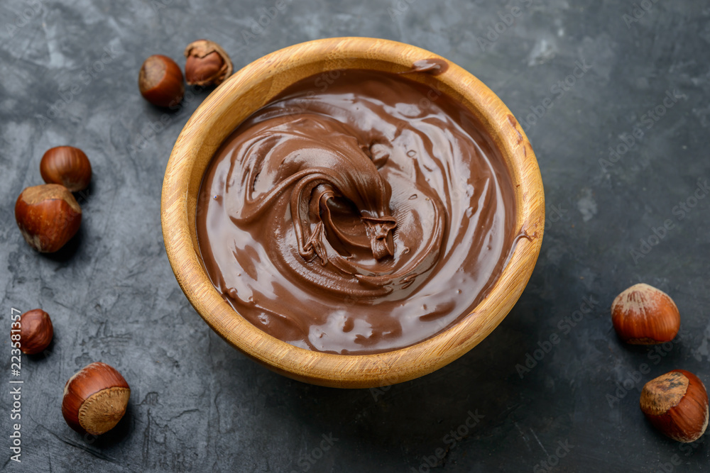 Chocolate cream in a bowl, nuts and chocolate pieces on dark table. Chocolate cream in a bowl, nuts and chocolate pieces on dark table.