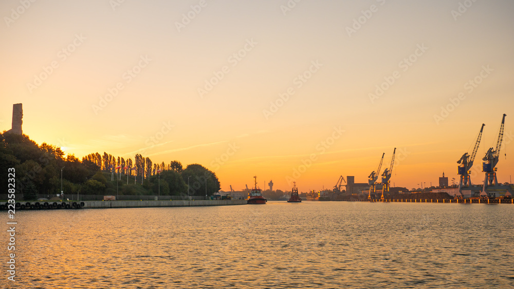 Ships in port at estuary of Vistula river at sunset time with view of the Westerplatte.
