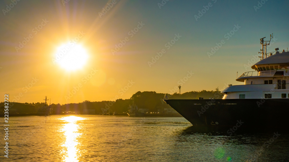 Ship sailing on a river during sunrise.