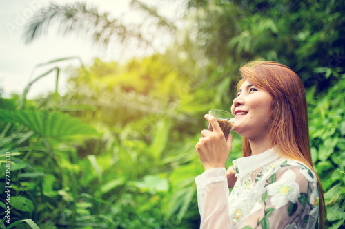 Young asian woman drinking a cup of coffee and enjoy nature view in morning.