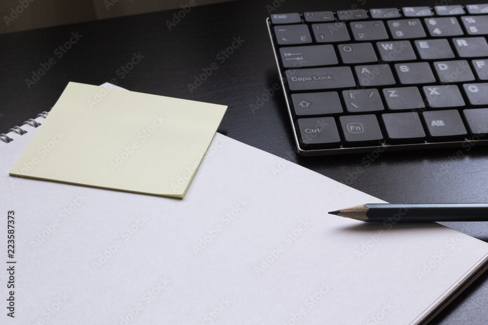 Notepad with a pencil on the table next to the keyboard Notepad with a pencil on the table next to the keyboard
