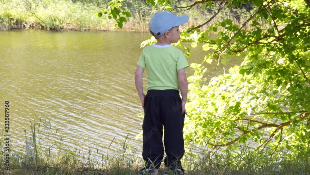 The child stands on the river bank and looks into the river. The child stands on the river bank and looks into the river.