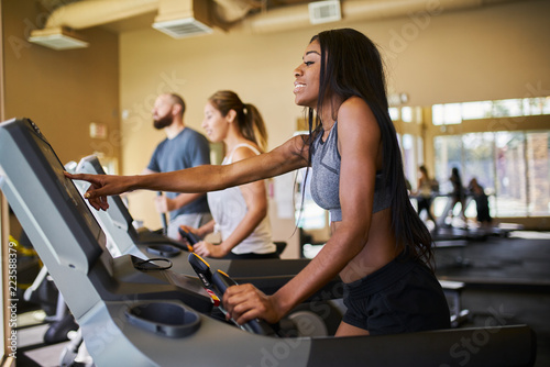 african american woman using treadmill in gym with other people